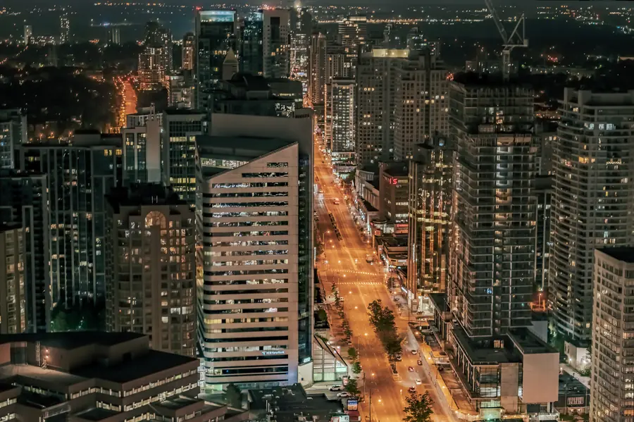 Toronto at night from above, a lit avenue cutting between rows of glowing high-rise towers