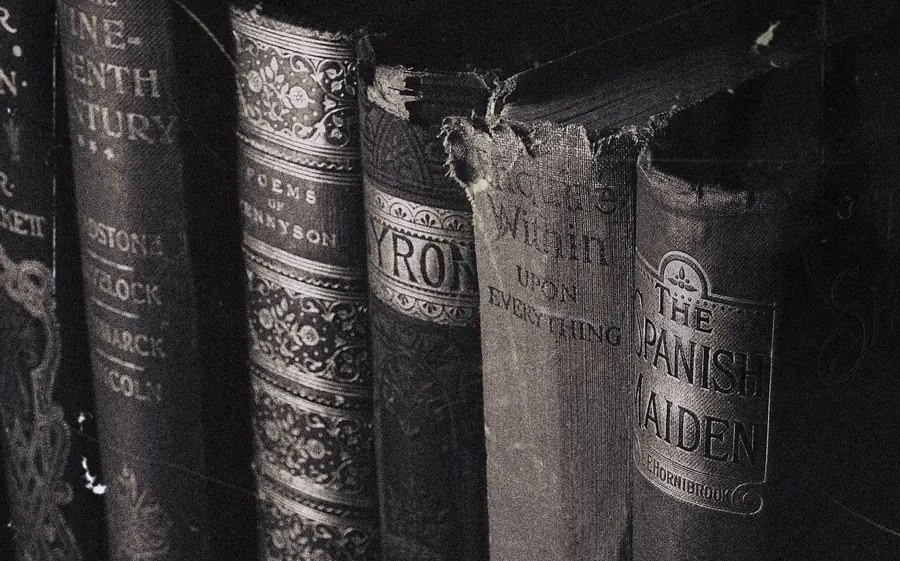 Row of worn Victorian hardcover spines, including volumes of Tennyson and Byron, photographed in sepia