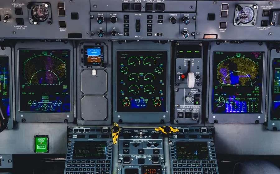 Cockpit-style control panel packed with green instrument displays, dials and warning switches